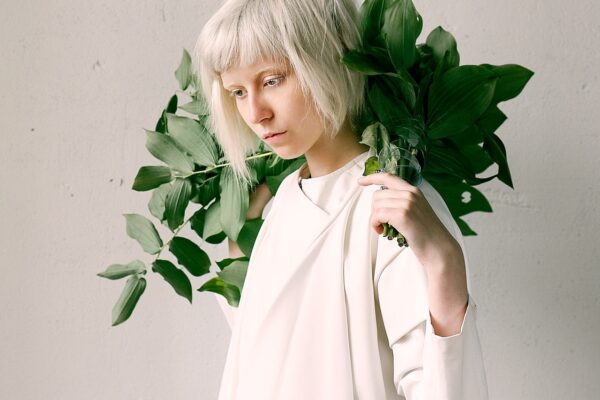 woman in white clothes with plants on her shoulders